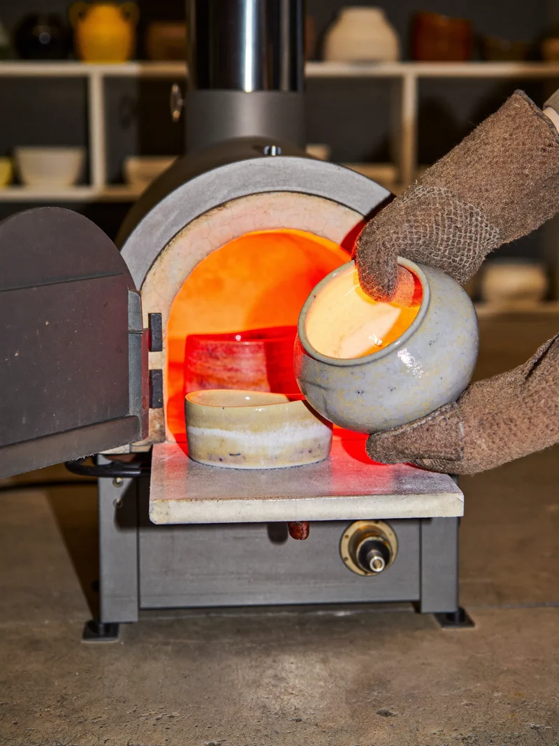Piccolo forno elettrico aperto: pezzi appena cotti sollevati con guanti resistenti al calore